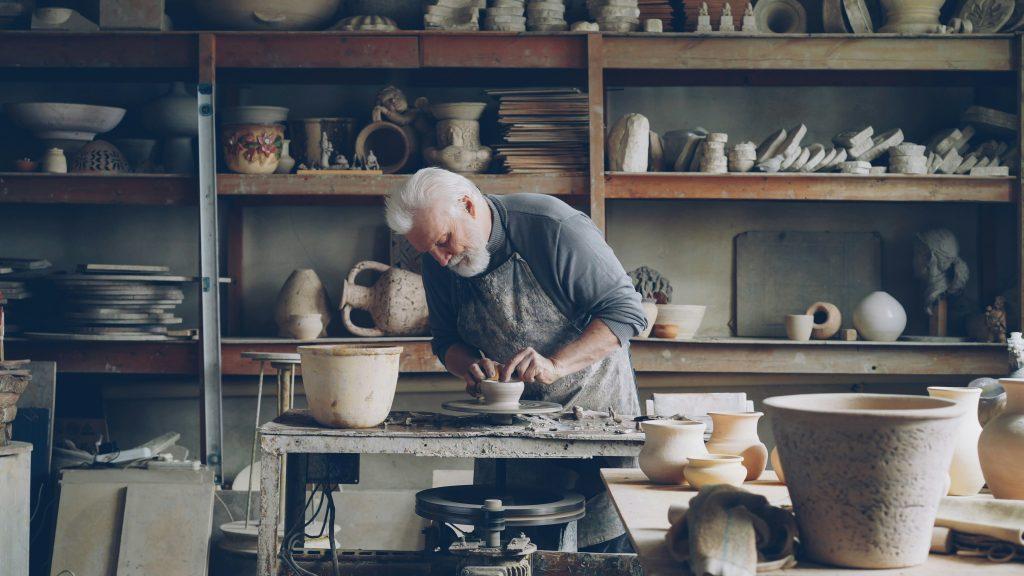Older potter working at a wheel in a pottery studio